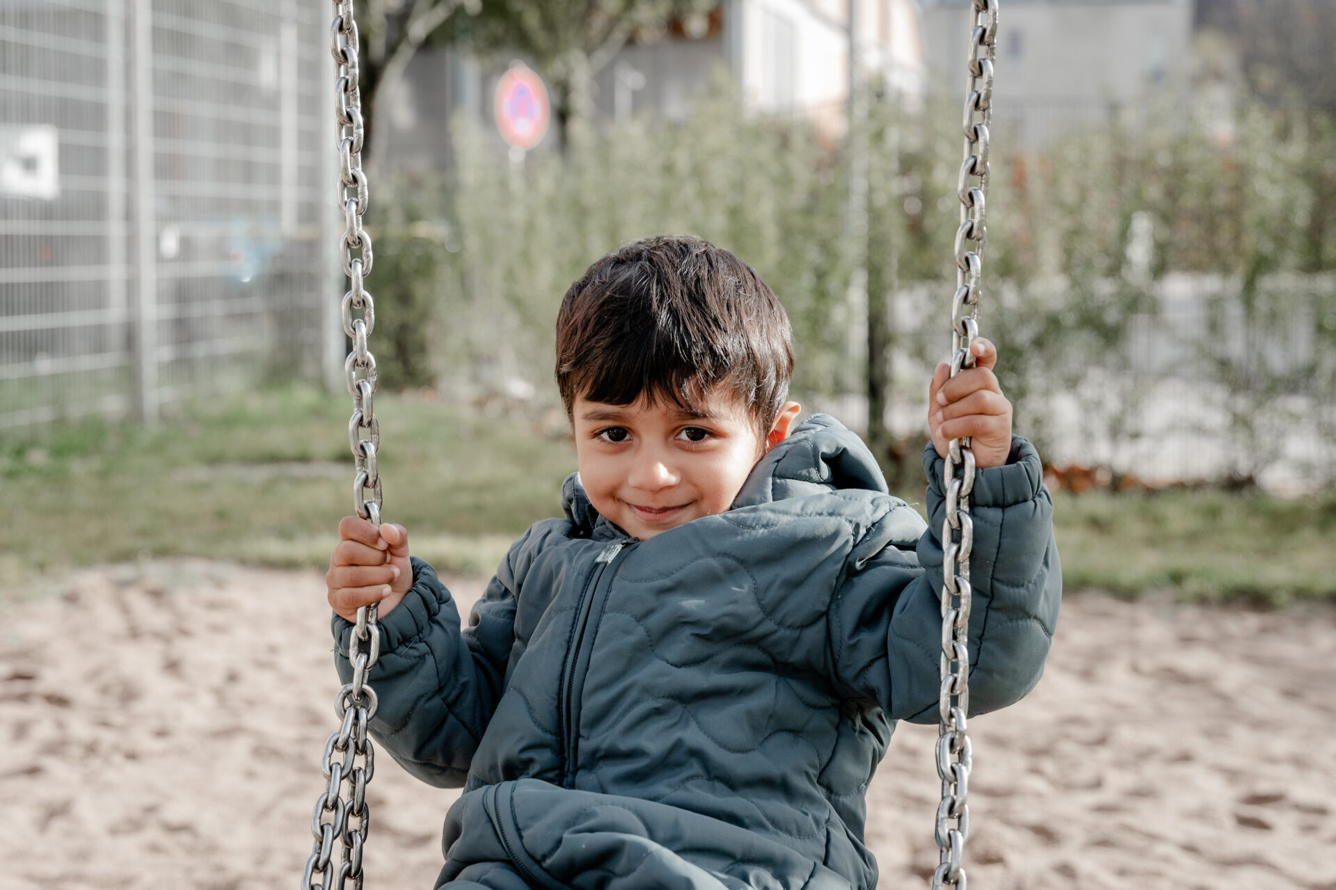 Junge schaukelt hoch auf dem Spielplatz – ungestellte Fotografie